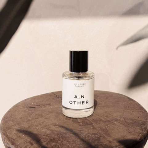 A.N. Other Ultimate Patchouli WF/2020 Parfum 50ML bottle on rustic wood pedestal with warm beige wall and botanical shadow.
