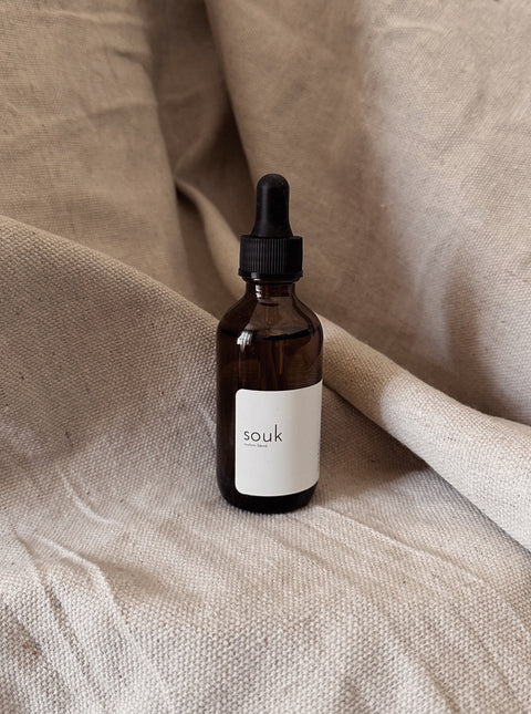 Souk Room Oil amber glass bottle on neutral linen background.