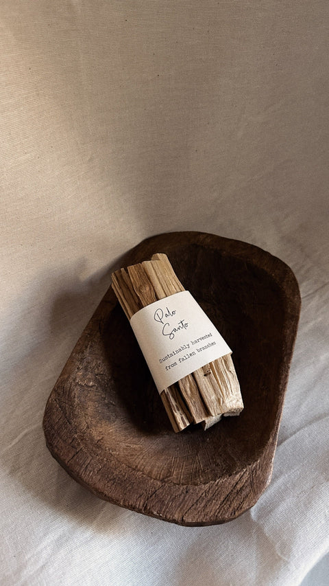 Palo Santo bundle with smoke styled on wooden bowl and neutral linen background.